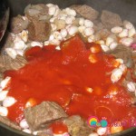 Dilute the tomato sauce with the water and pour into the pot with the meat and beans.